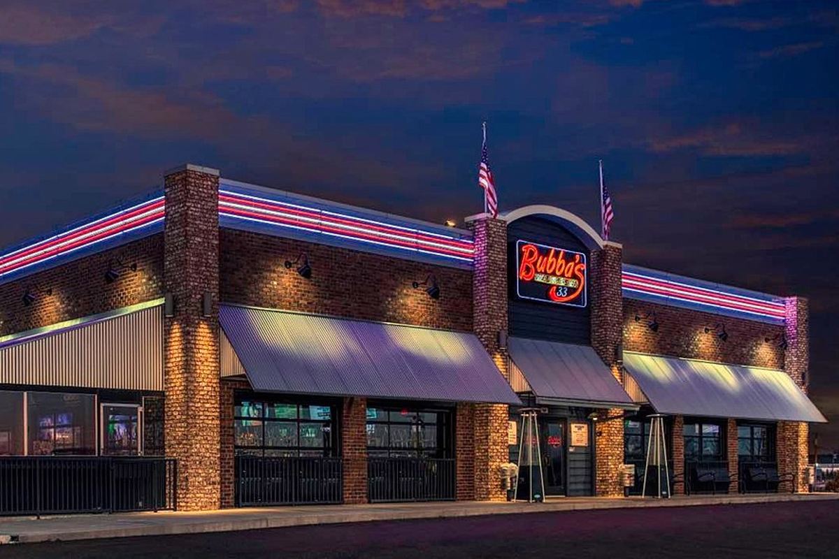 A Bubba's 33 restaurant exterior at dusk with its neon sign, from the brand's website