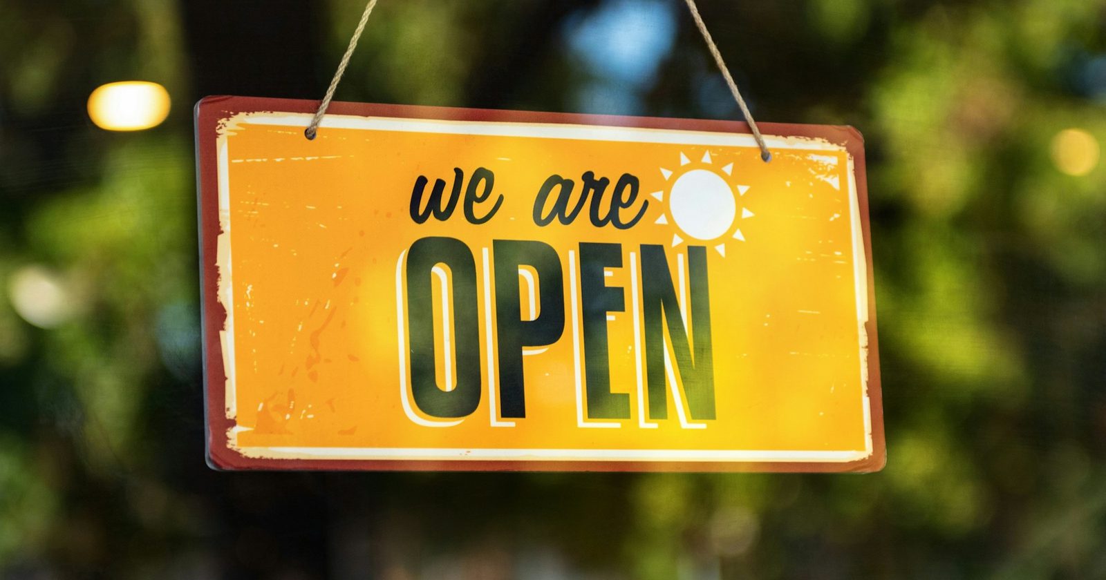 Yellow We Are Open sign hanging in a shop window, for a roundup of new restaurants and businesses in Southeast Texas