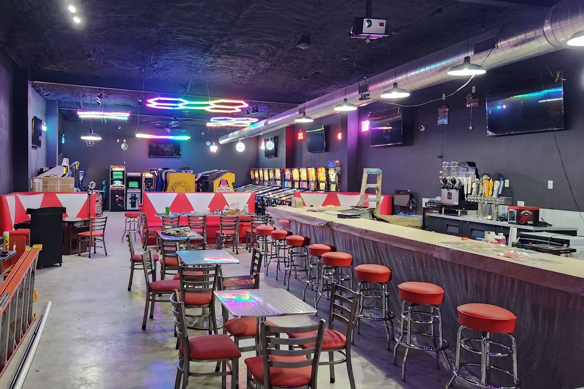 Rows of pinball machines, neon lights and red bar stools inside Kirby's Arcade before opening