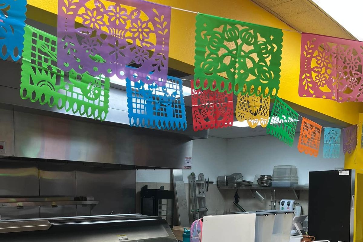 Las Chatas counter in Orange under strings of colorful papel picado, with the kitchen behind