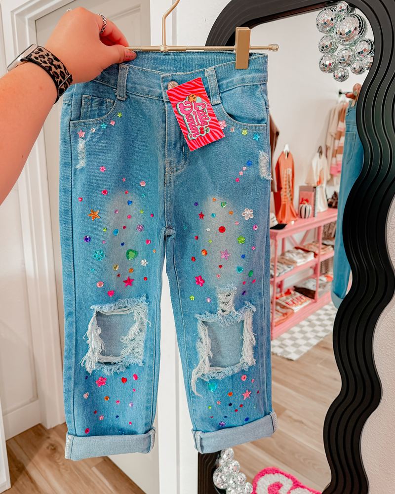 Hand-distressed, jewel-studded kids' jeans held up inside the Little Denim Co. shop