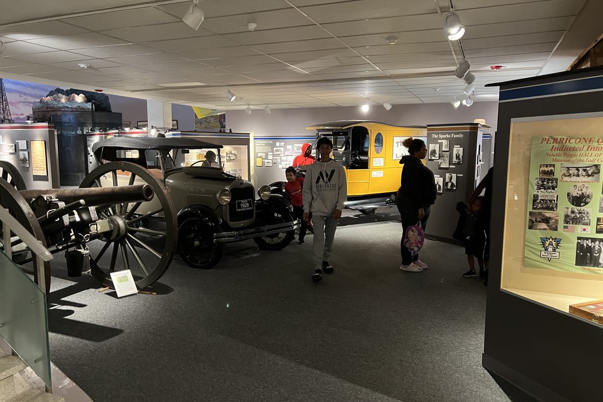Visitors walk through a gallery at the Museum of the Gulf Coast past an old field cannon, a 1928 Ford Model T and a yellow vintage truck